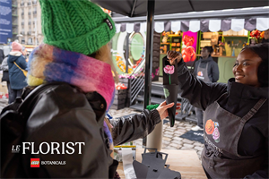 A woman on a market stall giving someone a Lego flower