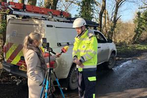 An electrical worker being interviewed on a road in a rural area.