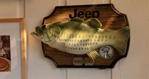 A Big Mouth Billy Bass animatronic fish on a Jeep-branded board hanging on a wall