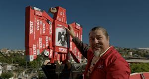 A man stand before a Tecate branded eagle sculpture