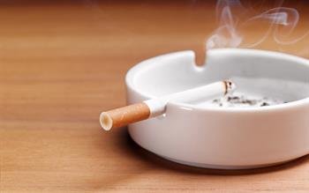 Lit cigarette resting in a white ash tray