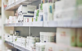 Boxes and bottles of medicines on shelves in a pharmacy dispensary.