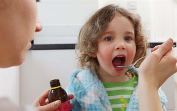 A child takes a spoonful of medicine.