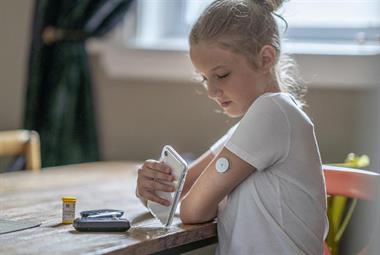 Child checking blood sugar using glucose monitoring system