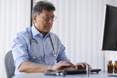 Male GP using a computer