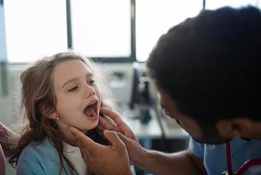 全科医生正在检查一个小女孩的喉咙