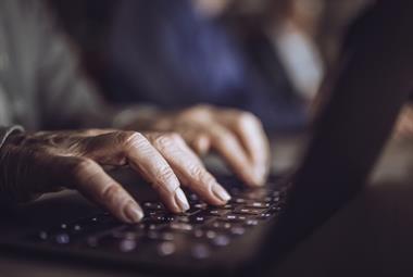Older person's hands typing on laptop keyboard