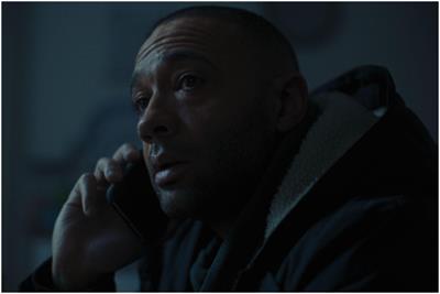 Darkly lit still from a British Gas ad showing a man on the phone