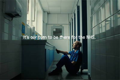 A screenshot of the Frontline19 TV ad, which features a nurse slumped in a bathroom and the superimposed text 'It's our turn to be there for the NHS'