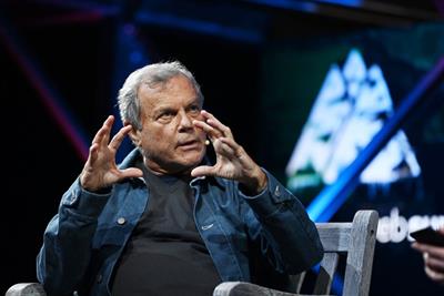 Martin Sorrell speaking on-stage at an event, gesticulating with cupped hands