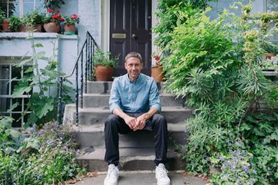 Guillermo Vega sitting on some stone steps surrounded by plants