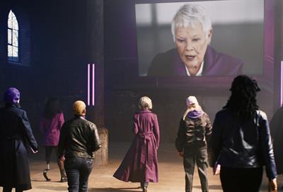 Photo of women walking towards a screen showing Dame Judi Dench