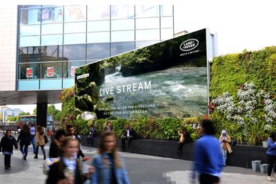 A live stream is shown on a giant billboard for Land Rover 