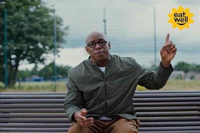 A still from the M&S ad of Ian Wright sitting on a bench pointing at the Eat Well logo