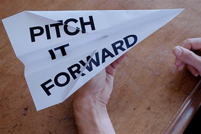 a paper plane with the words Pitch It Forward