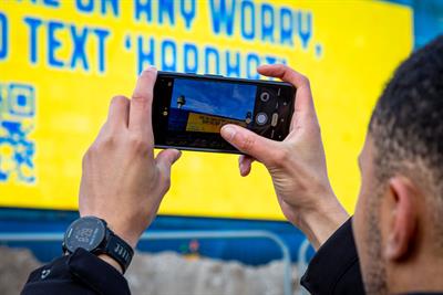 A man using his smartphone to photograph a 'live text' billboard
