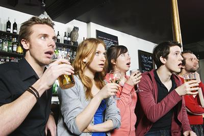 Patrons at a bar look stunned watching sport on TV. Photo: Getty Images