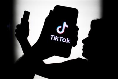A silhouette of person holding aloft of phono with the TikTok logo. Photo: Getty Images