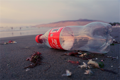 A single-use bottle of Coca-Cola stranded on a beach