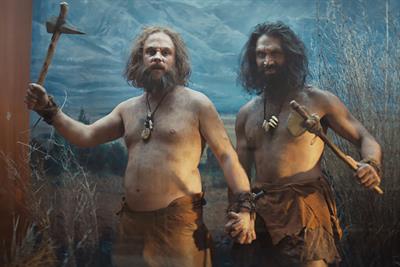 Two men dressed as cavemen holding hands