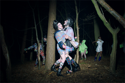 The cast, dressed in clothes by Charles Jeffrey, dance amongst the trees 
