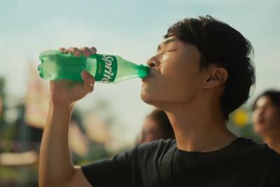 A man drinking from a bottle of Sprite
