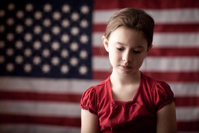 Sad looking girl in front of American flag