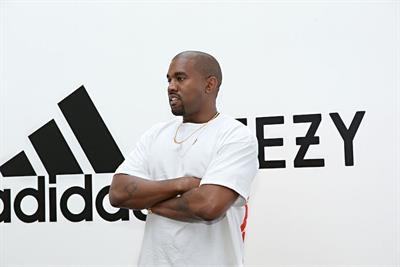 Kanye West standing in front of Adidas and Yeezy logos