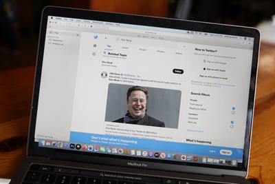 Laptop displaying Twitter feed with news stories about Elon Musk