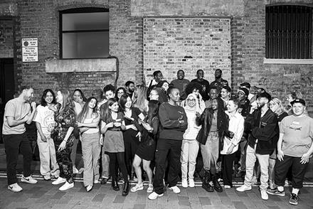 Black and white photo of a group of Brixton Finishing School students taking a break from lessons during a summer programme, pictured outside the Captify London offices in Covent Garden