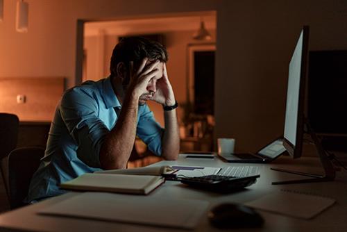 A man at a computer looking stressed