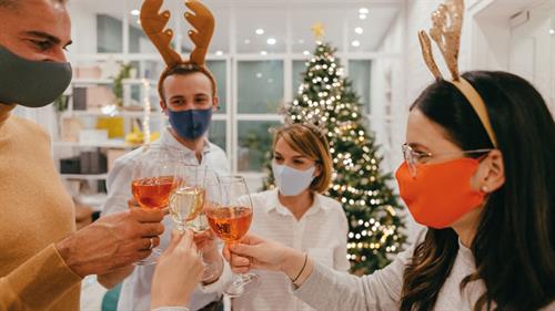 Group of colleagues with reindeer hats and face masks at the office Christmas party 