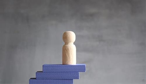Wooden person on a stair case of blocks