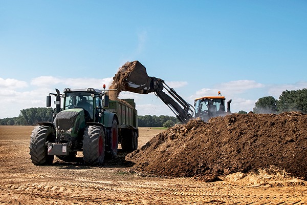 Excavator filling manure in the trailer of a tractor to fertilise the field. Photograph: Fermate/123RF