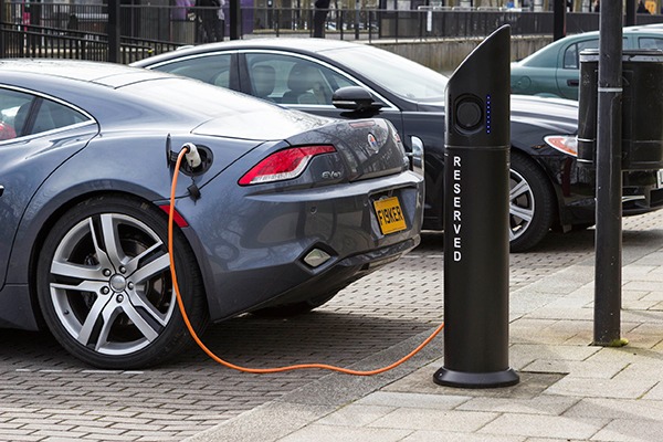Modern electric car charging at station dock point near parking lot, United Kingdom . Photograph: Olga Marc/123RF