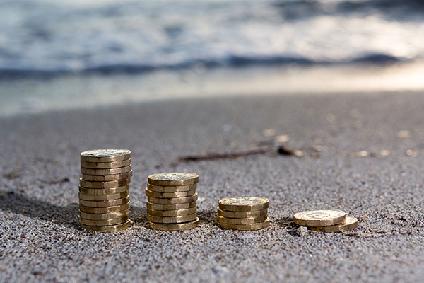 Row of pound coins piled on beach.
