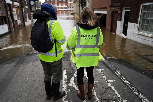 Two Environment Agency officers looking at a flooding street