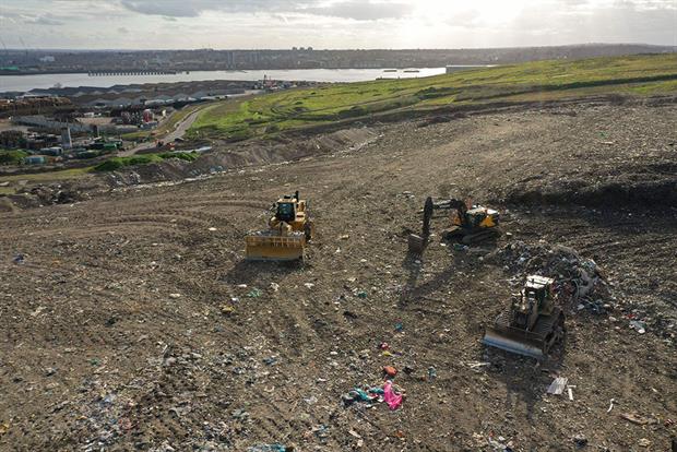 Bulldozers on a waste landfill with the river Thames in the background