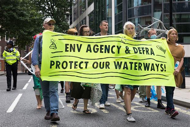 Extinction Rebellion protestors holding a banner that reads "Env Agency & DEFRA protect our waterways!"