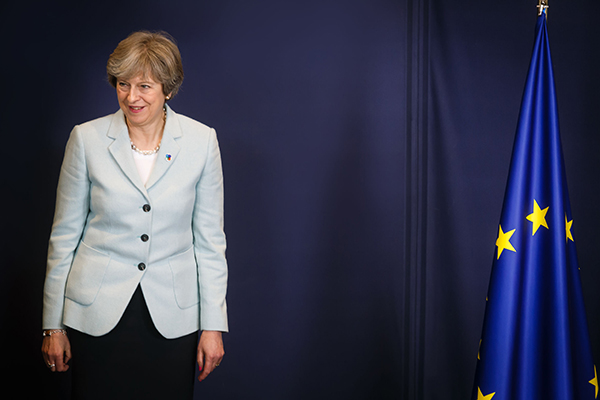 Theresa May standing next to EU flag