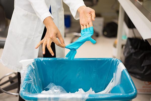 Medical worker putting plastic glove in bin