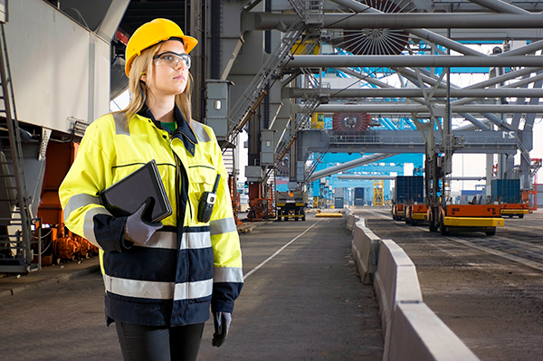 Woman in hi vis jacket with hard hat holding clipboard