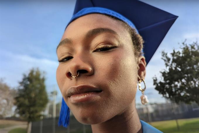 A young woman looks at the camera in her graduation cap