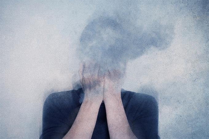 Figure with hands covering face covered in smoke, mental health and illness concept