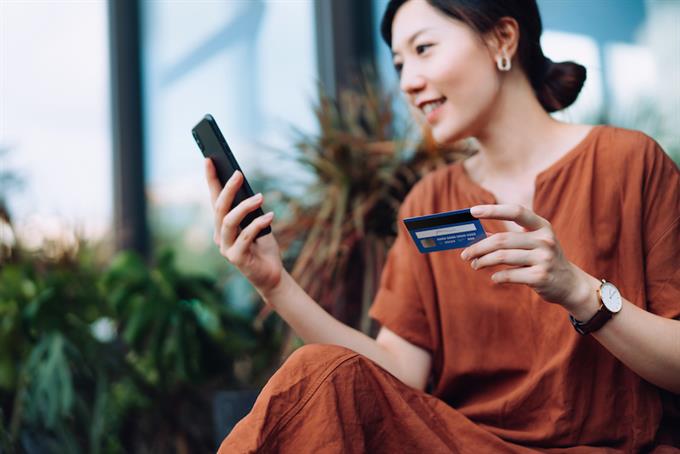 Woman holding credit card shopping online using her smart phone