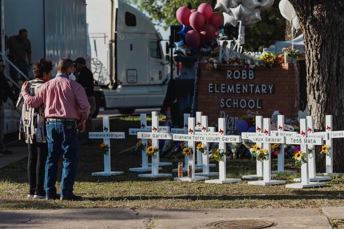 Mourners stand in front of memorial crosses at Robb Elementary School after the mass shooting that left 21 dead.