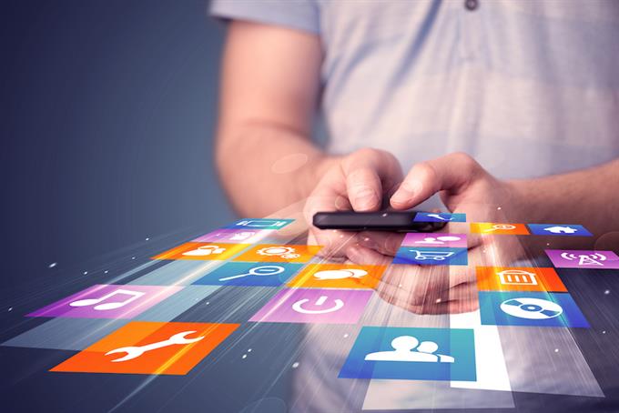 Man holding smart phone with virtual app icons floating from the screen