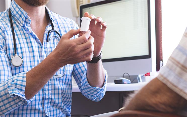 Doctor showing a pill bottle to a patient