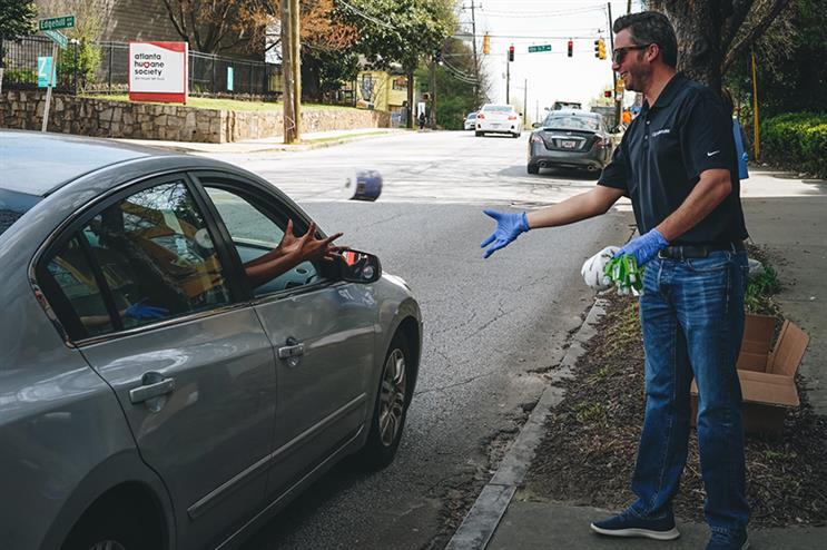 A.J. Whitehurst, director of field operations at GigaMonster tosses a roll of toilet paper into a waiting car. (Photo credit: Rose Rosenhauer, Trevelino/Keller)
