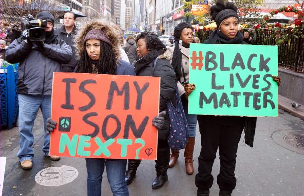  Protestors carrying placards at a Black Lives Matter demonstration in New York City (Image via Wikipedia Commons)